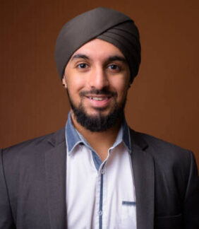 Studio shot of young bearded Indian businessman wearing suit and turban against colored background horizontal shot