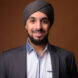 Studio shot of young bearded Indian businessman wearing suit and turban against colored background horizontal shot